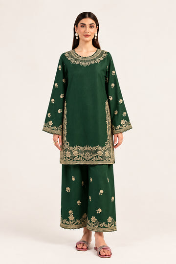 A woman modeling a dark green embroidered kurta and trouser set with beige floral patterns, set against a plain light background. The brand name 'MARYUM & MARIA' is visible in the top right corner.