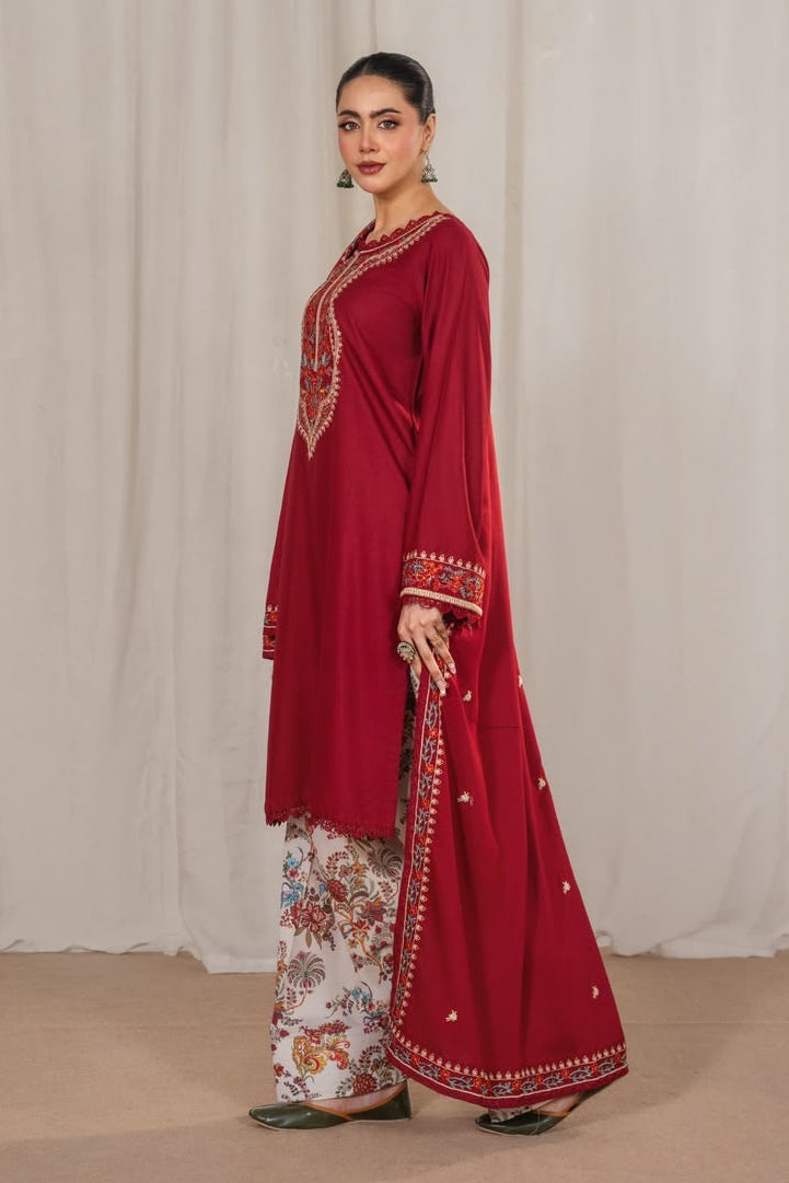 Woman wearing a red traditional outfit with floral patterns against a white curtain background
