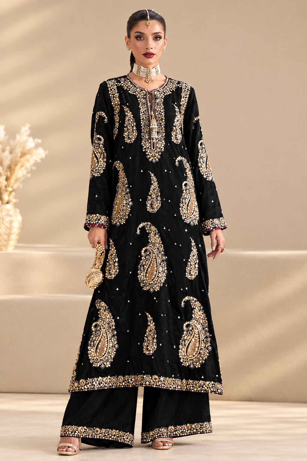A model wearing a black ethnic two-piece suit with intricate silver and gold paisley embroidery, shown in front and side views on a beige background. The image includes text overlays describing the components of the suit and a barcode.