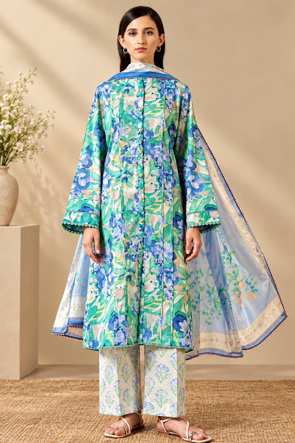 A model wearing a printed traditional kurta set stands against a beige wall on the left, with product details and text panels on the right. The set includes a light blue, green, and white floral print kurta and matching pants.