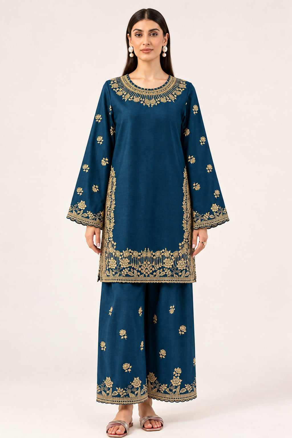 A woman modeling a navy blue traditional outfit with gold floral embroidery, consisting of a long-sleeve kurta and matching wide-leg pants, against a plain light background. The brand name 'MARYUM & MARIA' is visible in the top right corner.