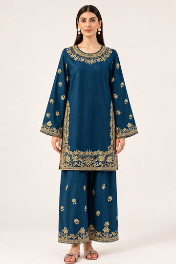 A woman modeling a navy blue traditional outfit with gold floral embroidery, consisting of a long-sleeve kurta and matching wide-leg pants, against a plain light background. The brand name 'MARYUM & MARIA' is visible in the top right corner.