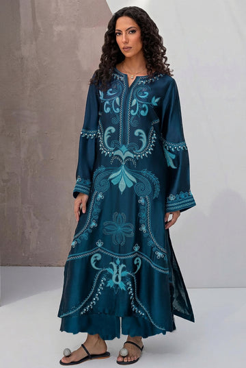 A model wearing a dark teal embroidered Dhanak kurta set, shown in a split-screen layout with text listing included pieces: embroidered shirt, dyed trouser, embroidered sleeves, and pashmina shawl. Brand name Nadia Farooqui is visible at the top.