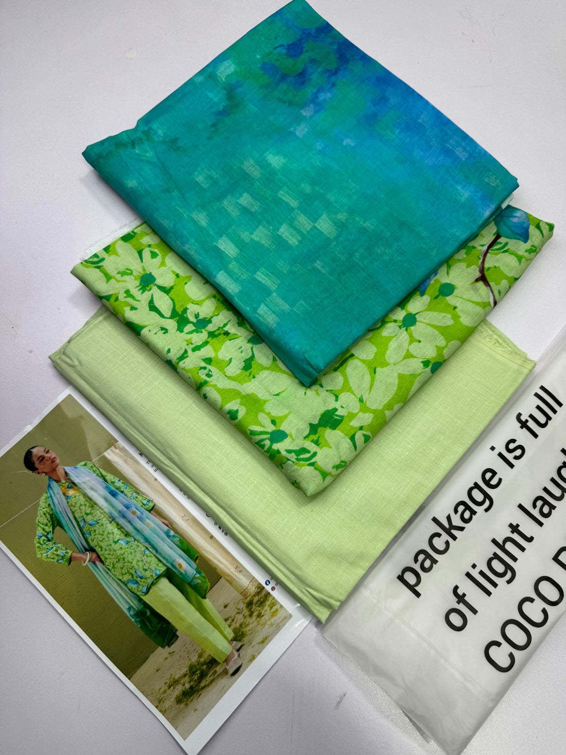 A catalog page for COCO by Liza Shakirman Prints, featuring a model wearing a green and blue printed traditional outfit with a matching dupatta on the left, and product details on the right including style name KAEL-7B, package contents, and care instructions.