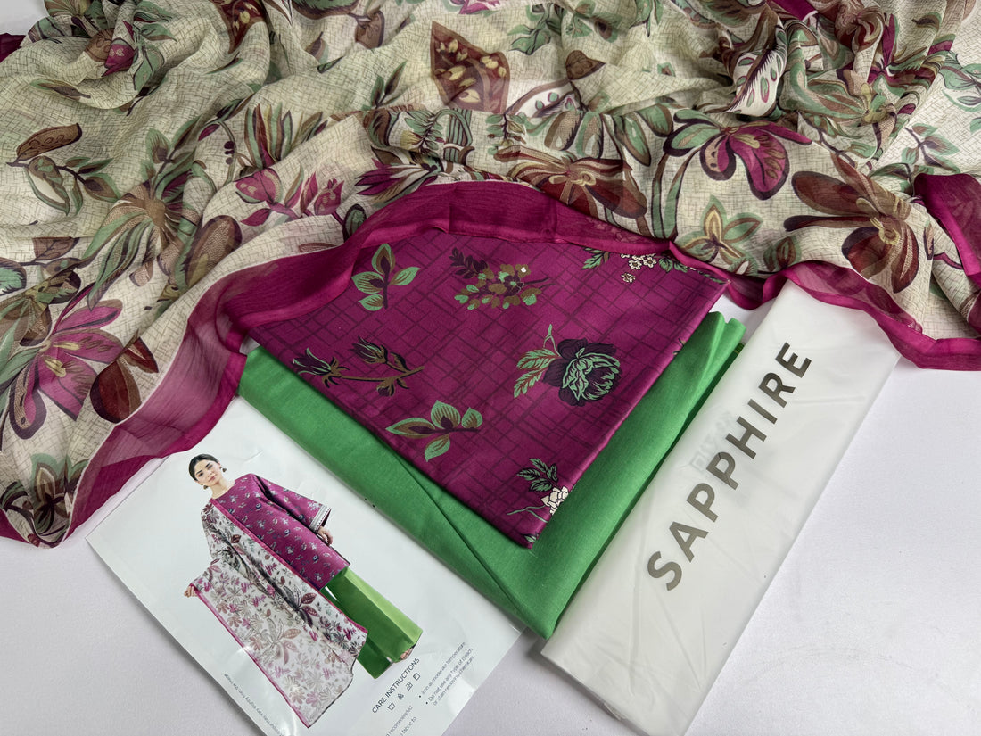 A fashion catalog page for a 3-piece printed lawn suit from Design Stock, featuring a model wearing a purple kurta with floral embroidery, green wide-leg trousers, and a matching floral dupatta. The right side contains product details, a barcode, and the brand name SAPPHIRE.