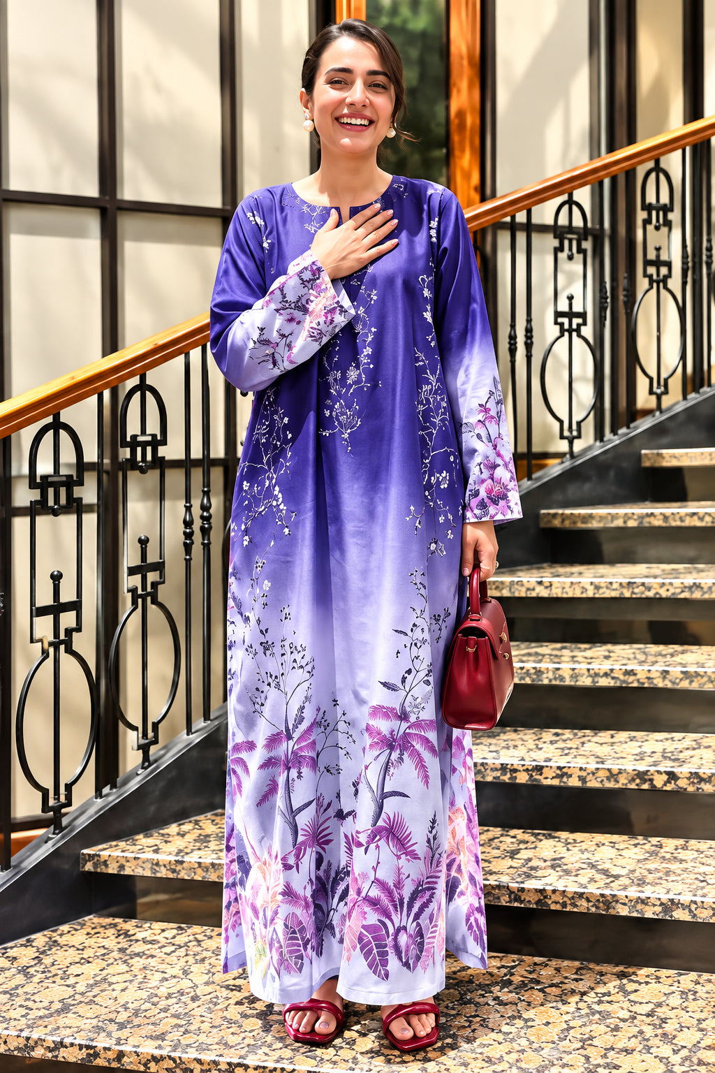 A woman modeling a two-piece silk printed outfit in a split-screen layout, with text details in the center. The outfit is a long-sleeve dress and trouser set in a purple-to-white gradient with floral patterns.