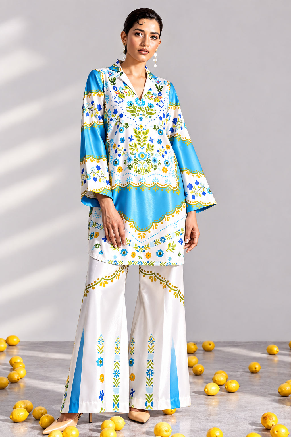 A model wearing a light blue and white printed two-piece kurta and trouser set from Ethnic Shop, shown on a split graphic background with product details and care instructions on the left.