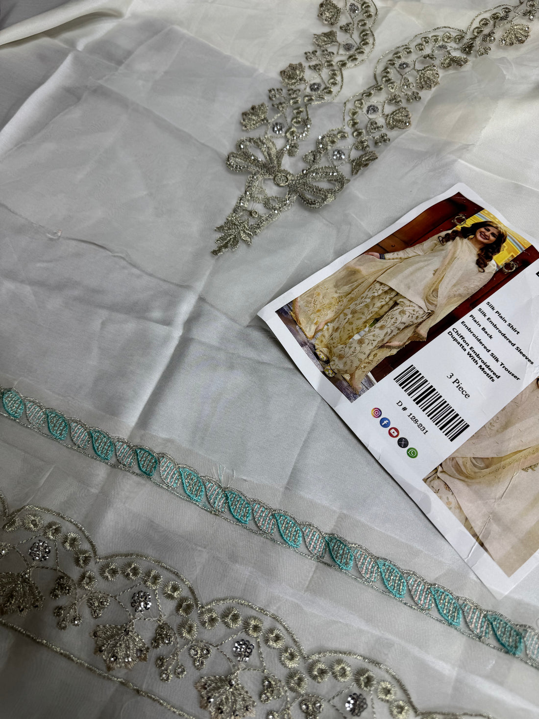 A composite catalog image showing a woman modeling a traditional South Asian outfit in two side panels, with a central text panel describing the garment details. The outfit is a cream/off-white three-piece set with beige and gold floral embroidery.