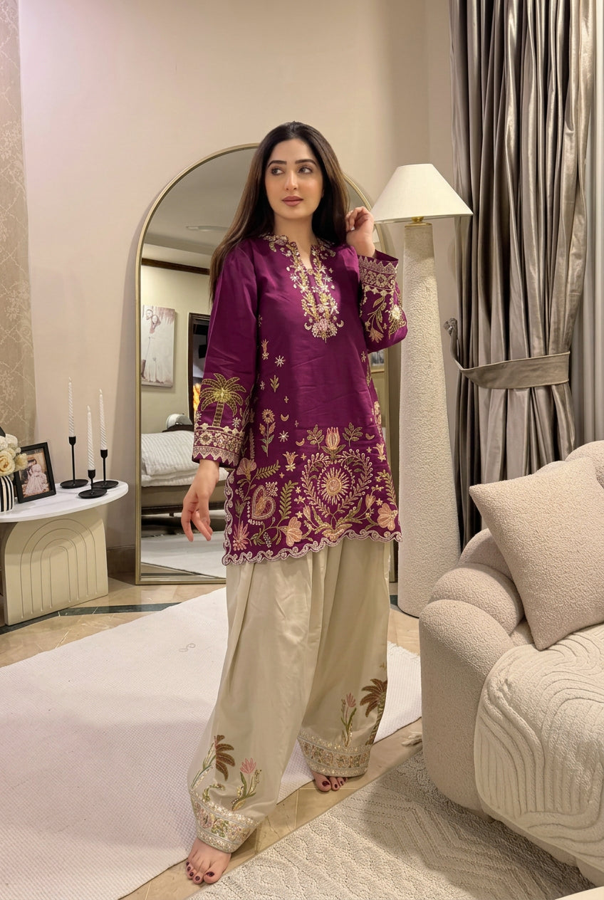 Woman in a purple embroidered outfit standing in a stylish living room.