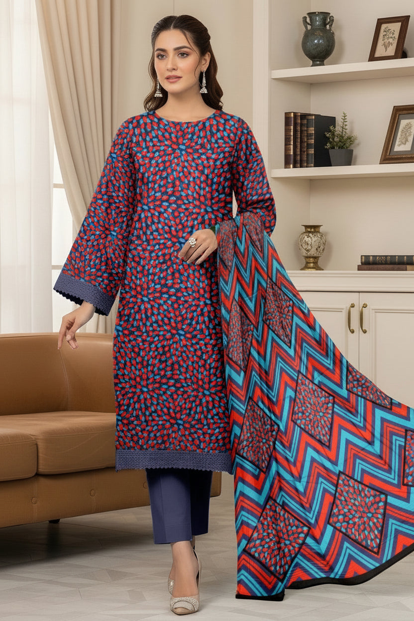A woman modeling a Kalkaram Bana Dora collection three-piece suit. The outfit consists of a blue and red patterned kurta, dark blue pants, and a matching patterned dupatta draped over her shoulder.
