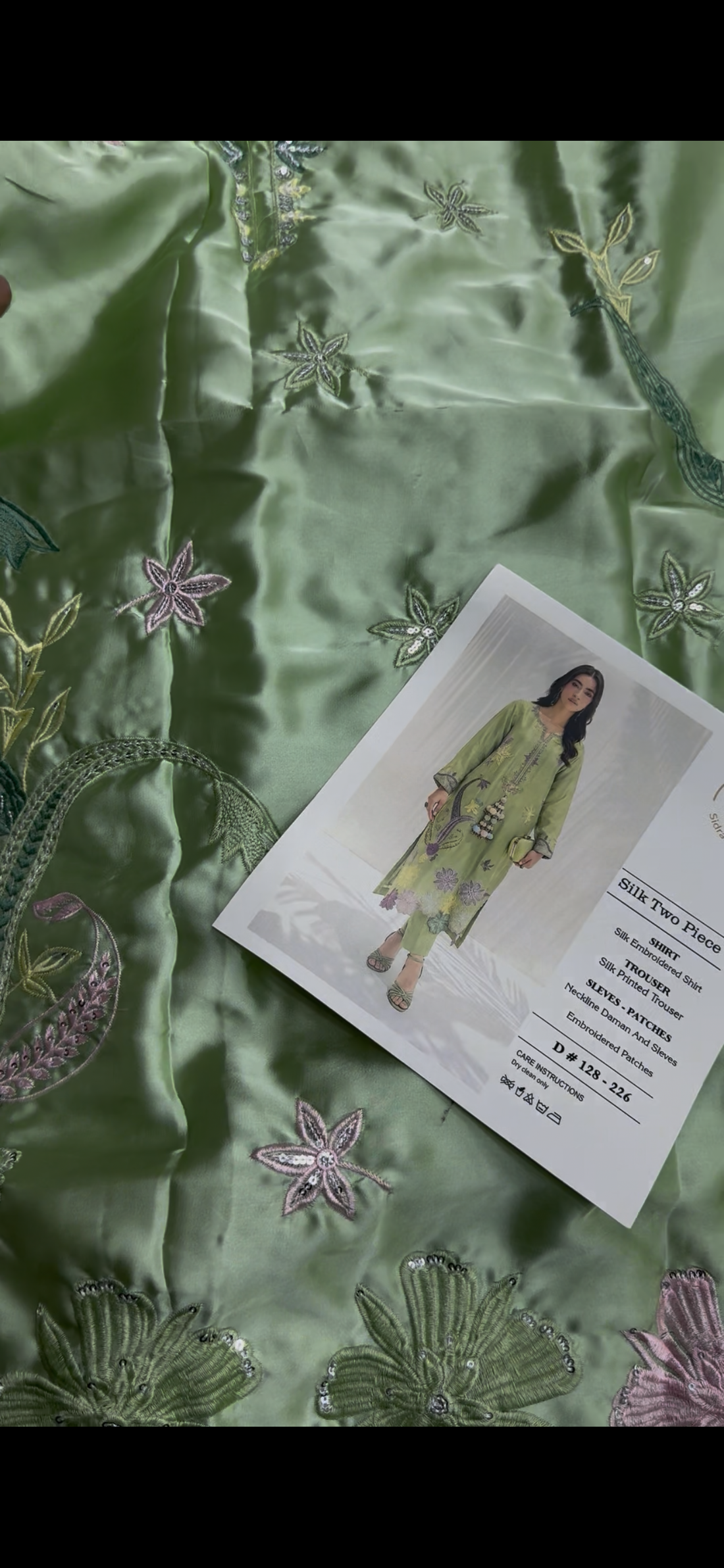 A woman models a light green silk two-piece kurta set with colorful floral embroidery, shown next to product specifications and care instructions on a white background. The brand logo 'Sidrah & Sarah' is visible in the top right.