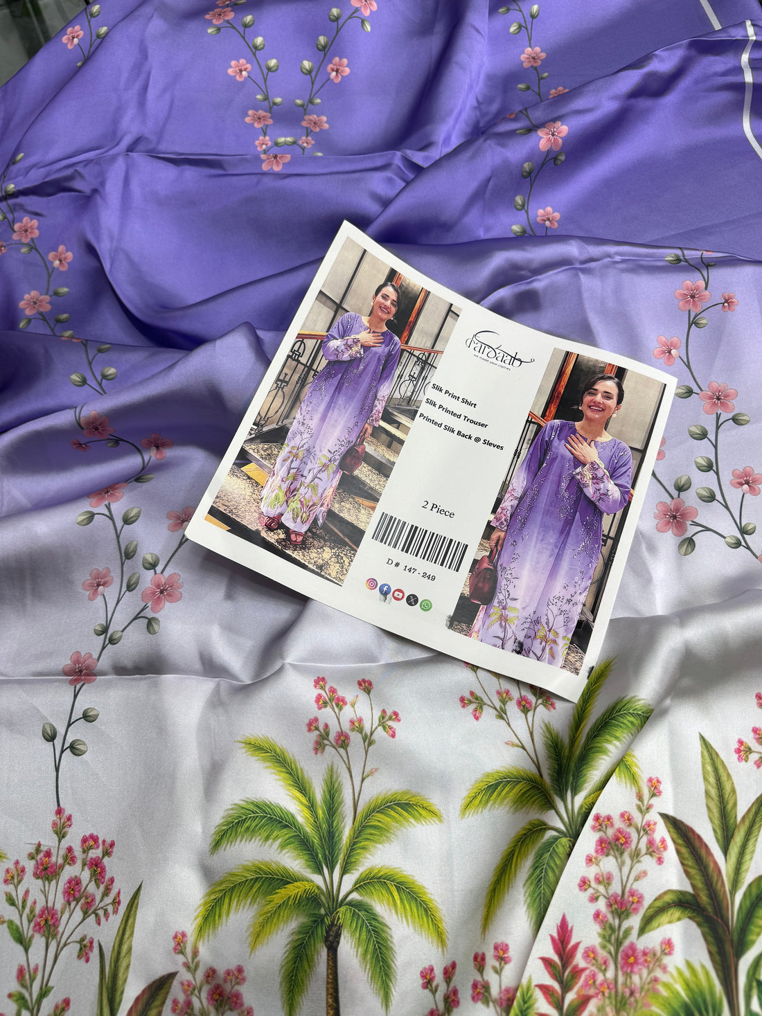 A woman modeling a two-piece purple printed outfit consisting of a long-sleeve satin shirt and trousers, shown in a split-screen presentation with text details in the center.