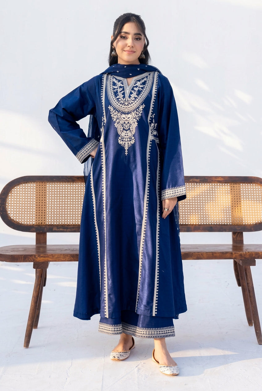 A woman modeling a navy blue long kurta with intricate silver embroidery on the chest and borders, standing in front of a wooden bench against a white background.