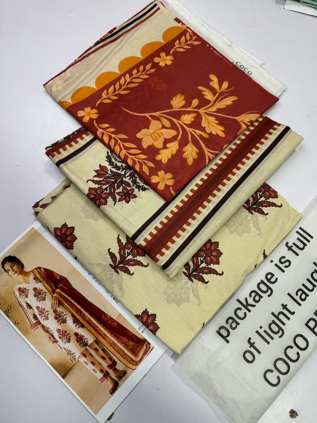 A promotional catalog page for ZARA SHAHJAHAN COCO Prints Dlox, featuring a model on the left wearing a cream-colored kurta and trousers with rust-red and brown floral patterns and a matching dupatta, alongside product details and a QR code on the right.