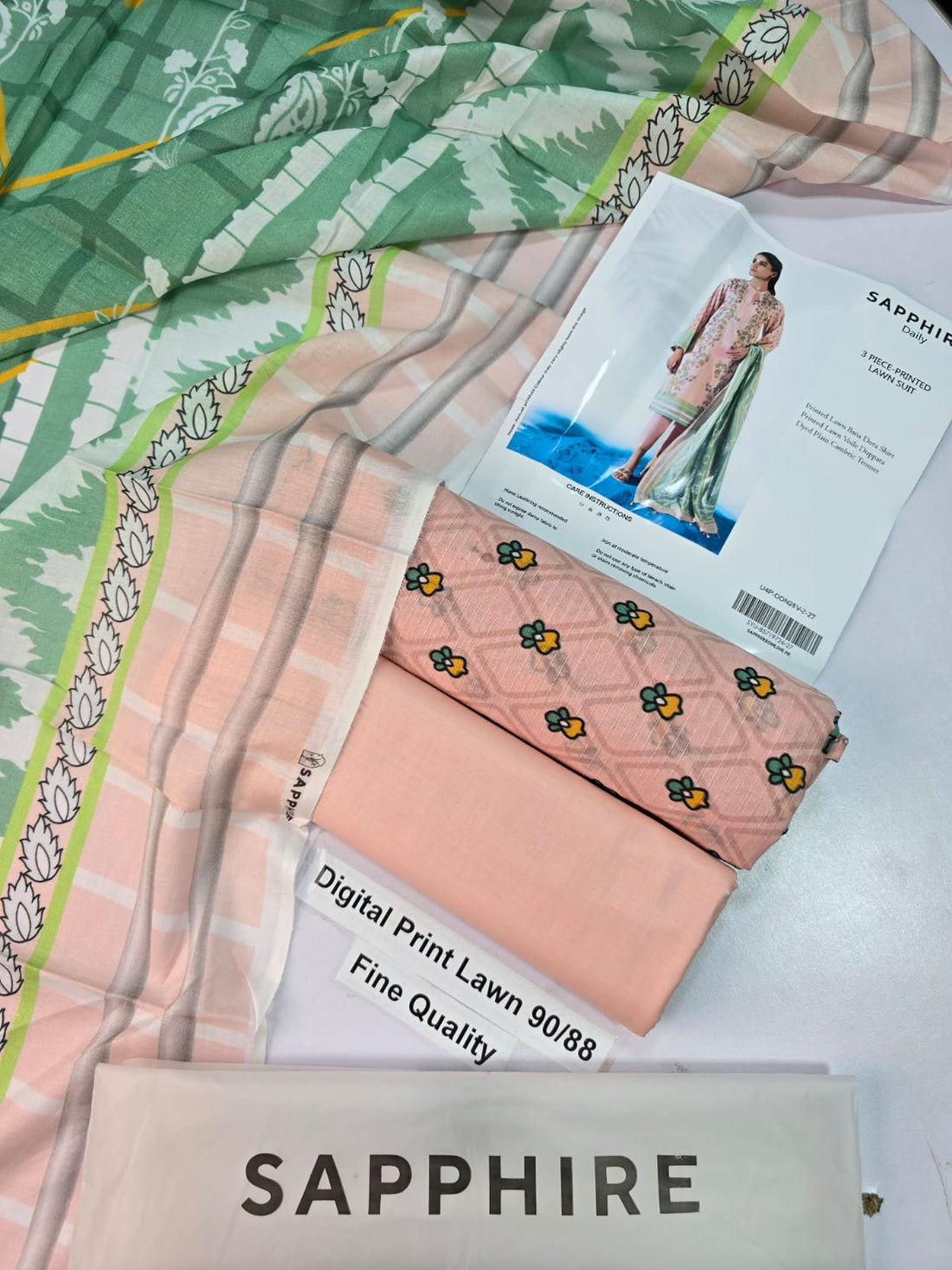Sapphire Daily 3-piece printed lawn suit sewing pattern cover, featuring a model wearing a beige kurta with green and pink floral prints, a light green salwar, and a matching dupatta.