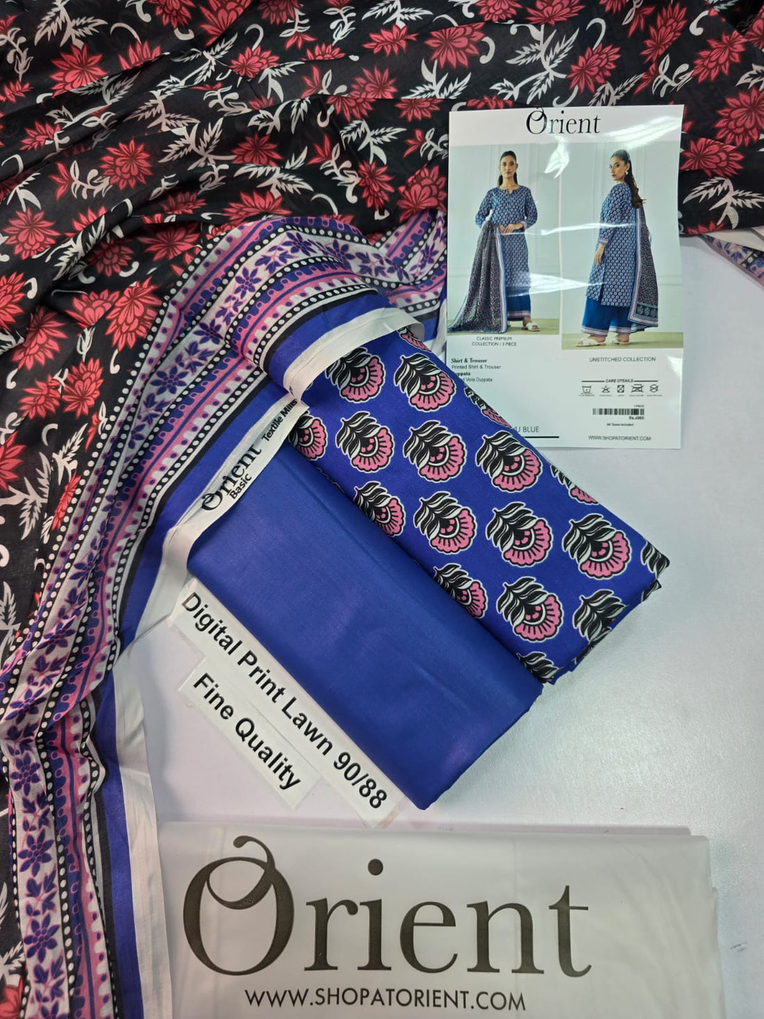 A catalog-style product image for an 'Orient' women's unstitched collection, showing a model in two views wearing a blue printed kurta and trousers set with a dupatta. The left view shows the front, and the right view shows the back.